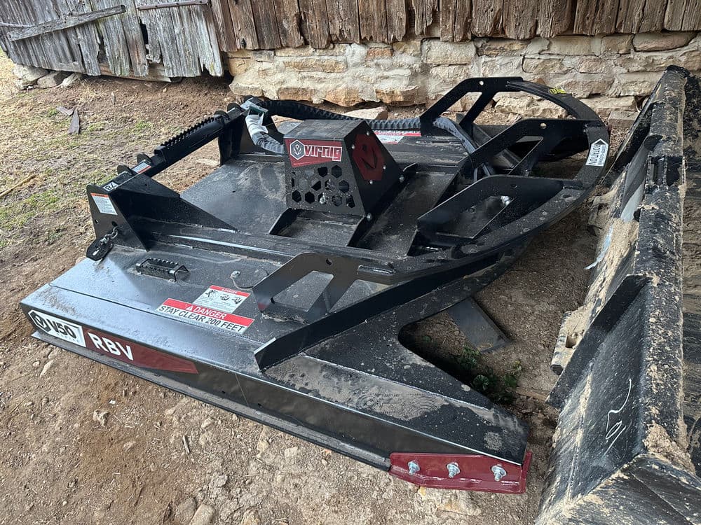 Vicon RBV rotary cutter attachment resting on the ground near a barn wall.
