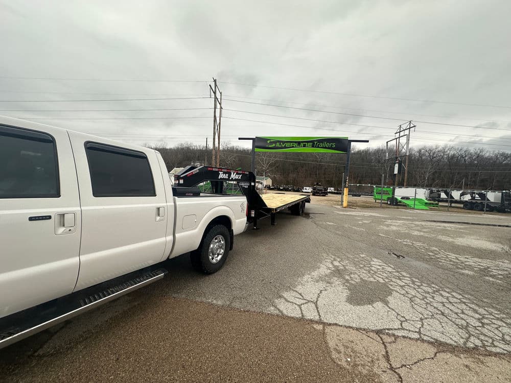 White truck towing trailer at Silverline Trailers dealership on a cloudy day.
